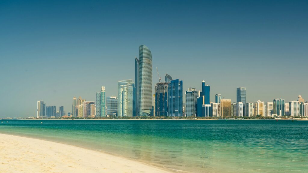 Abu Dhabi skyline seen across the water from a beach